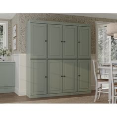 an image of a kitchen setting with green cupboards and white dining room furniture in the background