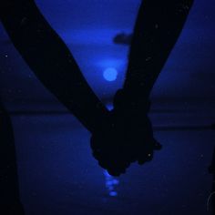 two people holding hands in the dark with blue light shining on them and one person's hand reaching for something