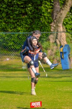 a man and woman are playing soccer on the grass with trees in the back ground