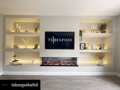 a television mounted on the side of a white wall next to bookshelves filled with plants