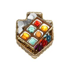 a basket filled with assorted candies on top of a white table next to coins