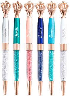 four different colored pens with gold crowns on top and one has glitter in the middle