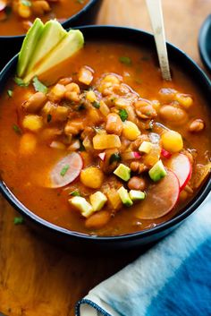 two bowls filled with beans and avocado on top of a wooden table