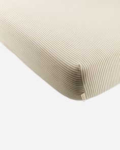 a close up view of the side of a bed with ticking fabric on it and a white background