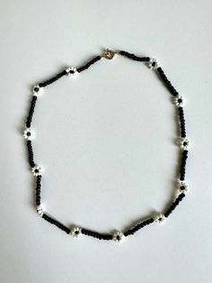 Elevate your style with this stunning black and white flower beaded choker necklace. Handcrafted with care, this unique piece blends elegance with a touch of edginess, making it perfect for any occasion. The monochrome color scheme ensures versatility, complementing both casual outfits and evening ensembles effortlessly. Whether you're treating yourself or searching for a thoughtful gift, this choker promises to add a dash of floral charm to your jewelry collection. Embrace timeless beauty with our black and white flower choker today! Details: ☆ Handmade item! ☆ Length: 15 in ☆ Perfect for: Everyday wear, special occasions, gifts Please make sure your address is correct before purchasing! For any questions don't hesitate to contact me :) Handmade Black Flower Necklace, Black Flower-shaped Jewelry With Colorful Beads, Trendy Black Flower-shaped Jewelry, Adjustable Black Flower Pendant Necklace, Black Flower Choker As A Gift, Black Flower Pendant Necklace With Charm, Black Adjustable Flower Pendant Necklace, Black Flower Choker For Gifts, Black Beaded Flower Necklace