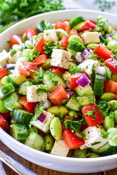 a white bowl filled with cucumber, tomato and feta cheese salad