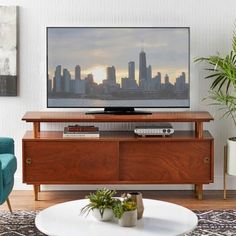 a flat screen tv sitting on top of a wooden entertainment center next to a blue chair