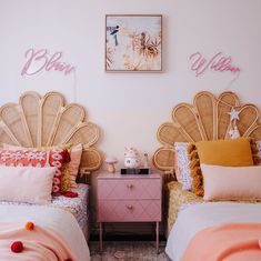 two twin beds with pink and gold decor in a girls'bedroom, one is made out of wicker