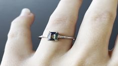 a woman's hand with a ring on it that has an emerald stone in the middle