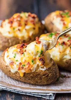 a fork is lifting up some baked potatoes with cheese and bacon on them, sitting on a plate