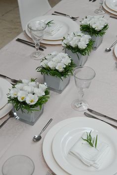 the table is set with white flowers and place settings