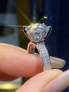 a diamond ring being held by someone's hand