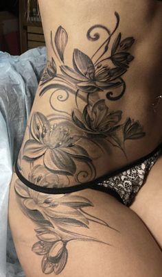 a woman's stomach with flowers and vines on the side, in black and white