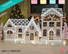 some paper cut out houses on a table with christmas trees and lights in the background