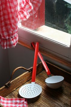 a red and white checkered table cloth hanging from a window sill next to an ironing board