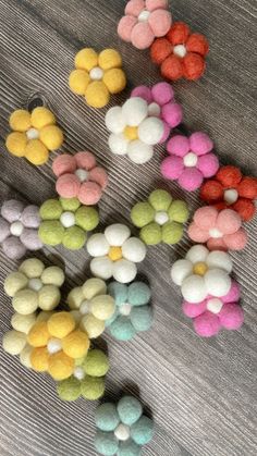 several different colored pom poms on a wooden surface