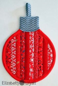 a christmas ornament hanging on the wall with red and gray fabric, along with silver thread