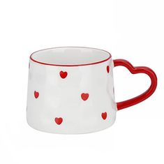 a red and white mug with hearts on the inside is sitting in front of a white background