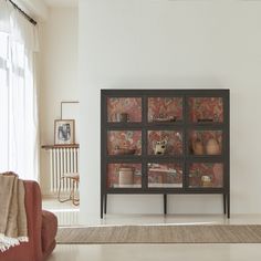 a living room with a couch, chair and glass cabinet in the middle of it