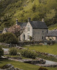 a stone house in the middle of a lush green hillside