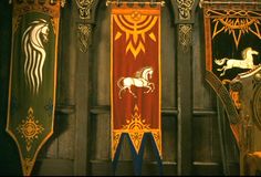 three decorative banners with horses on them in front of a black wall and clock tower