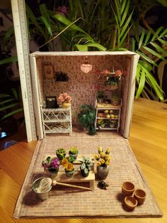 a doll house with potted plants and other items on the table in front of it