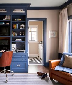 a living room with blue bookcases and a brown leather chair