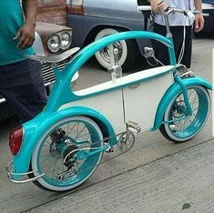 a blue and white bike parked on the side of a road next to a car