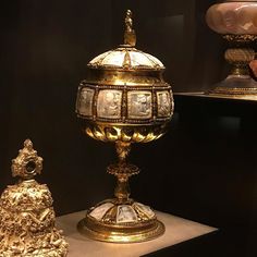 an elaborately decorated golden egg on display in a museum case with other gold objects around it