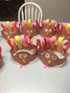 a table topped with paper turkeys on top of a white table covered in orange and pink strips