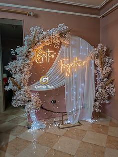 the entrance to a room decorated with white flowers and drapes, is lit up by neon lights