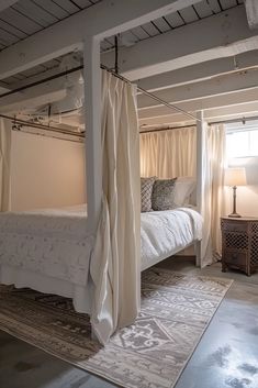 a white bed sitting in a bedroom next to a window with curtains on top of it