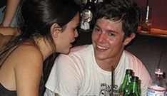 two people sitting at a table with beer bottles