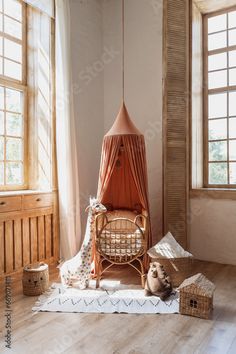 a room with wooden floors, windows and a hammock hanging from the ceiling