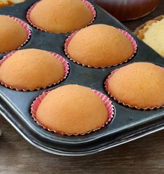 a muffin tin filled with cupcakes on top of a wooden table next to other pastries