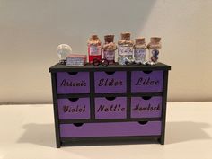 an assortment of spices sitting on top of a purple drawer with labels that say, amenii elder lilat, violet nettle and hummush