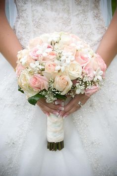 a bridal holding a bouquet of pink and white flowers on her wedding day,