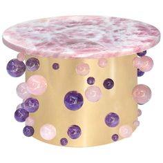 a pink and gold coffee table with balls on the top, against a white background