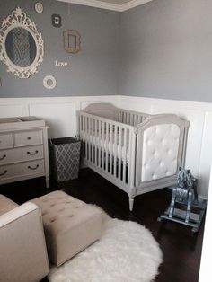 a baby's room with gray walls and white furniture