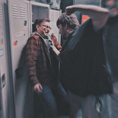 two men standing next to each other in front of lockers with their mouths open