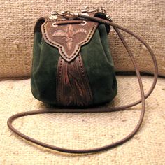 a green purse sitting on top of a couch next to a white pillow and a brown leather strap