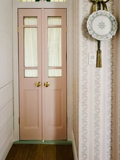 a pink door in the corner of a room with a plate on the wall next to it