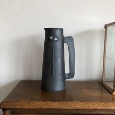 a black vase sitting on top of a wooden table