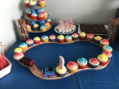 a table topped with cupcakes and cakes next to a blue tablecloth covered table