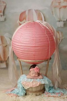 a baby in a basket with a pink paper lantern