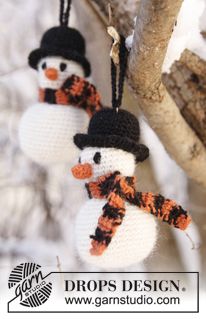 two knitted snowmen hanging from a tree