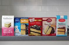 several boxes of cake mix sitting on top of a counter next to cakes and milk