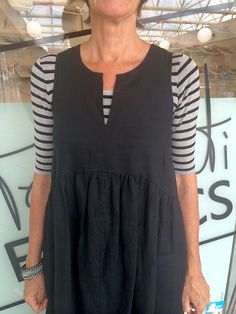 an older woman standing in front of a surfboard with her hands on her hips