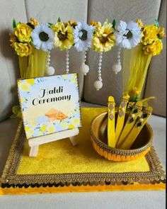 a table topped with yellow and white flowers next to a sign that says jadi ceremony