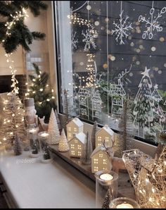 a window sill filled with lots of christmas decorations and lit up houses in front of it